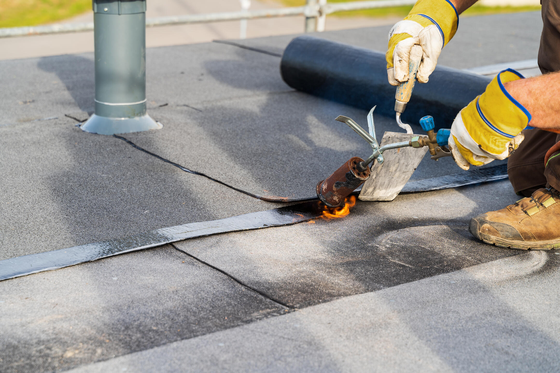 commercial roof leak repair-close up of a roof tech repairing a section of commercial roofing